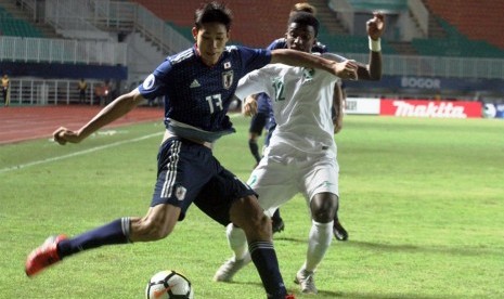 Pemain Jepang U-19 Taichi Hara (kiri) berebut bola dengan pemain Arab Saudi U-19 Mohammed Ali (kanan) pada semifinal Piala AFC U-19 di Stadion Pakansari, Bogor, Jawa Barat, Kamis (1/11/2018). Arab Saudi mengalahkan Jepang 2-0 dan melaju ke final. 