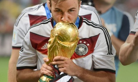   Pemain Jerman Mario Goetze mencium piala dunia setelah tim Jerman berhasil menjadi juara sepak bola dunia FIFA di Estadio do Maracana, Rio de Janeiro, Brasil, Ahad (13/7). (EPA/MARCUS BRANDT)