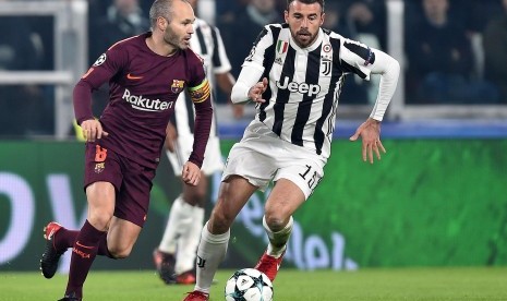 Pemain Juventus Andrea Barzagli (kanan) dan Andres Iniesta dari Barcelona beraksi saat pertandingan sepak bola kualifikasi Liga Champions UEFA antara Juventus FC dan FC Barcelona di Stadion Allianz di Turin, Italia, Kamis (23/11) dini hari WIB.