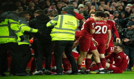 Pemain Liverpool Andy Robertson duduk di tanah setelah pergelangan kakinya dihantam oleh penyusup lapangan dalam pertandingan sepak bola Liga Primer Inggris antara Liverpool FC dan Manchester United di Anfield, Senin (6/3/2023) dini hari WIB.