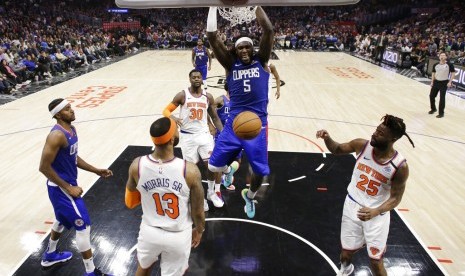 Pemain Los Angeles Clippers Montrezl Harrel (tengah) melakukan dunk di tengah penjagaan para pemain New York Knicks.