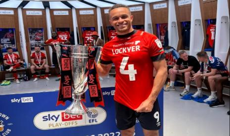 Pemain Luton Town Carlton Morris memegang trofi pemenang playoff Divisi Championship yang diganjar tiket promosi ke Liga Primer Inggris musim depan. Luton mengalahkan Coventry City 6-5 lewat adu penalti di Stadion Wembley.