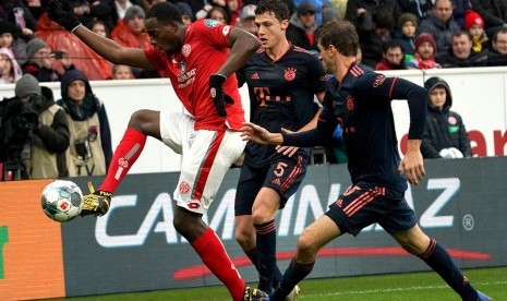 Pemain Mainz Moussa Niakhate (kiri) dijaga penyerang Bayern Muenchen Thomas Mueller (kanan) dalam pertandingan sepak bola Liga Jerman antara Mainz 05 dan FC Bayern Muenchen di Mainz, Jerman, Sabtu (1/2).