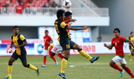 Pemain Malaysia Ahmad Hazwan Bakri (depan) berduel udara dengan bek Indonesia Manahati Lestusen pada laga semifinal SEA Games.