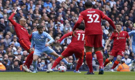 Pemain Manchester City Bernardo Silva, kedua dari kiri, berduel memperebutkan bola dengan pemain Liverpool Fabinho, kiri, dan pemain Liverpool Mohamed Salah dalam pertandingan sepak bola Liga Inggris antara Manchester City dan Liverpool, di stadion Etihad di Manchester, Inggris, Ahad, 10 April 2022 .