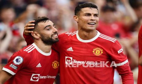 Pemain Manchester United  Bruno Fernandes (kiri) sedang diberi ucapan selamat oleh rekan setimnya Cristiano Ronaldo setelah mencetak gol ketiga timnya pada pertandingan sepak bola Liga Premier Inggris antara Manchester United dan Newcastle United di Manchester, Inggris, Sabtu (11/9).