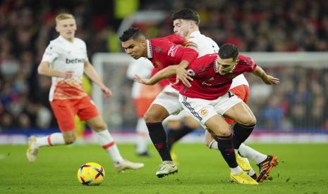  Pemain Manchester United Diogo Dalot (kanan) dan Casemiro Manchester United, kiri, berebut bola dengan pemain West Ham Declan Rice selama pertandingan sepak bola Liga Inggris antara Manchester United dan West Ham United di stadion Old Trafford di Manchester, Inggris,   Senin (31/10/2022) dini hari WIB. 