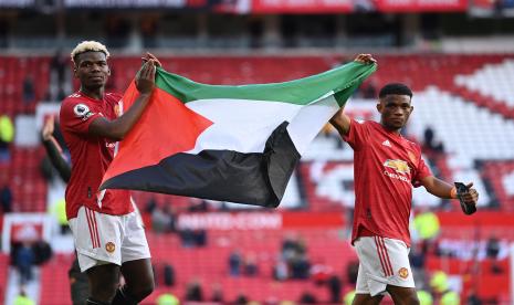 Pemain Manchester United Paul Pogba (kiri) dan Amad (kanan) mengibarkan bendera Palestina ketika menyampa suporter setelah pertandingan sepak bola Liga Primer Inggris antara Manchester United dan Fulham FC di Manchester, Inggris, 18 Mei 2021. 