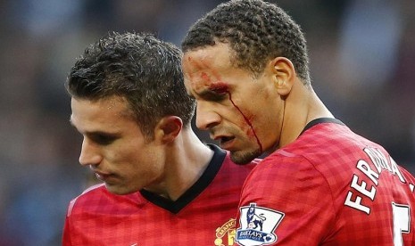  Pemain Manchester United Rio Ferdinand dibantu rekannya  Robin van Persie, setelah dihantam oleh sebuah benda yang dilemparkan dari arah penonton saat bertanding melawan Manchester City di Stadion Etihad di Manchester,Ahad (9/12). (Reuters/Phil Noble)