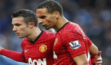  Pemain Manchester United Rio Ferdinand dibantu rekannya  Robin van Persie, setelah dihantam oleh sebuah benda yang dilemparkan dari arah penonton saat bertanding melawan Manchester City di Stadion Etihad di Manchester,Ahad (9/12). (Reuters/Phil Noble)