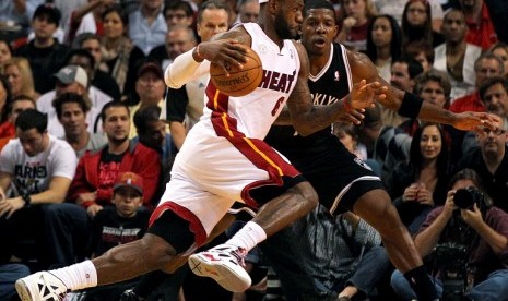 Pemain Miami Heat LeBron James berusaha melewati pemain Brooklyn Nets Joe Johnson dalam pertandingan NBA Rabu (7/11) di Miami