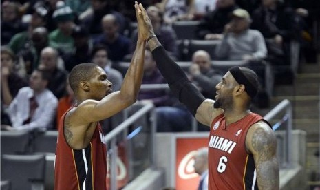 Pemain Miami Heat, LeBron James (kanan) dan Chris Bosh, melakukan high five saat menghadapi Toronto Raptors di laga NBA di Toronto pada Ahad (17/3). 