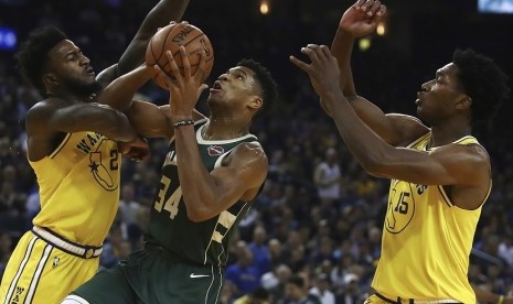 Pemain Milwaukee Bucks, Giannis Antetokounmpo (tengah) berada di tengah adangan dua pemain Golden State Warriors. 