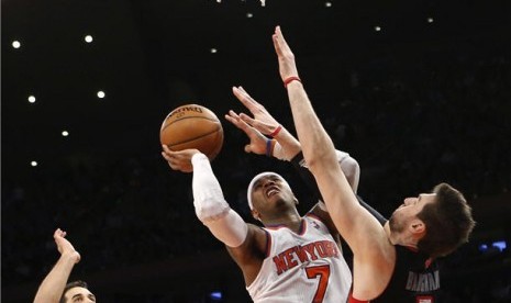 Pemain New York Knicks, Carmelo Anthony (tengah), melakukan drives menembus pertahanan pemain Toronto Raptor, Andrea Bargnani (kanan), di pertandingan NBA di New York pada Rabu (13/2).  