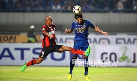 Pemain Persib Bandung Dedi Kusnandar (biru) menyundul bola dibayangi pemain Persipura Ricardo Salampessy.