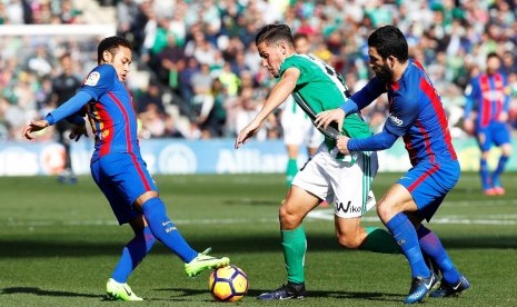 Pemain Real Betis Alex Alegria (tengah) berusaha melewati dua pemain Barcelona. 