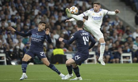 Pemain Real Madrid, Fede Valverde (kanan) mencoba merebut bola dari pemain City, Aymeric Laporte (tengah) dan Joao Cancelo (kiri) pada pertandingan leg kedua babak semifinal Liga Champions di Stadion Santiago Bernabeu, Kamis (5/5/2022) dini hari.