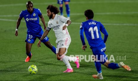 Pemain belakang Real Madrid Marcelo (tengah), berlari dengan bola di sebelah pemain Getafe Alena (kanan) dan Allan Nyom pada pertandingan sepak bola La Liga Spanyol antara Getafe dan Real Madrid di Stadion Alfonso Perez di Getafe, Spanyol, Senin (19/4) dini hari WIB.