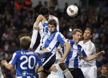 Pemain Real Madrid, Raphael Varane (atas), terlibat duel udara dengan pemain Real Sociedad, Inigo Martinez (tengah), di laga La Liga Spanyol di Stadion Santiago Bernabeu, Madrid, Sabtu (24/3). 