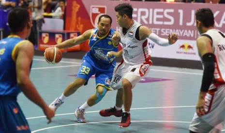 Pemain Satria Muda Pertamina Arki Dikania Wisnu membawa bola berusaha melewati pemain Aspac dalam pertandingan IBL.