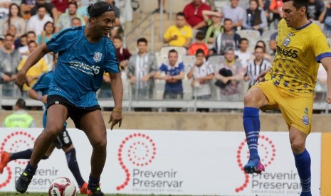 Pemain sepak bola Brasil Lucio (kanan) berebut bola dengan Ronaldinho Gaucho (kiri) saat acara amal di Stadion Mineirao di Belo Horizonte, Brasil, 8 Desember 2017. Laga bertajuk ’Game of Dreams' ini juga menjadi perayaan 15 tahun Brasil meraih Piala Dunia kelima. 