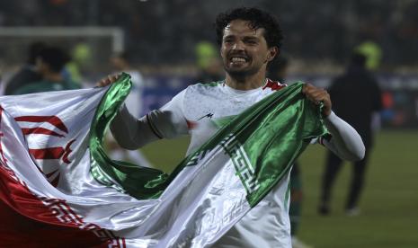 Pemain sepak bola Iran Omid Nor Afkan membawa bendera nasionalnya saat ia merayakan kelolosan dari kualifikasi untuk Piala Dunia 2022 Qatar setelah mengalahkan Irak, di Stadion Azadi di Teheran, Iran, Kamis, 27 Januari 2022. Iran menjadi tim pertama dari Asia yang lolos ke Piala Dunia 2022 bersama tuan rumah Qatar, setelah kemenangan 1-0 atas Irak. 