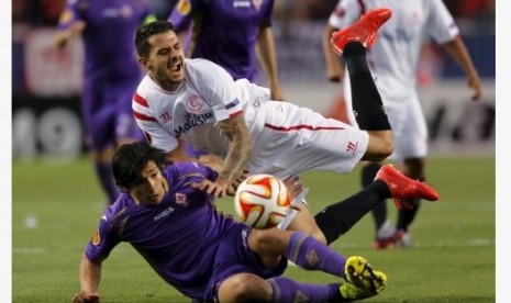 Pemain Sevilla Victor 'Vitolo' Machin (putih) jatuh di samping pemain Fiorentina Matias Fernandez dalam leg pertama semifinal Liga Europa di Ramon Sanchez Pizjuan, Jumat (8/5) WIB.