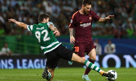 Pemain Sporting Cristiano Piccini (kiri) berusaha merebut bola dari kaki pemain Barcelona Lionel Messi ketika kedua tim bertemu pada Liga Champions Grup D di Stadion Jose Alvalade, Lisbon, Portugal, Kamis (28/9) dini hari WIB.