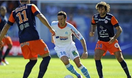 Pemain Tengah Marseille Morgan Amalfitano di hadang pemain Montpellier Emmanuel Herrera (kiri) dan Romain Pitau (Kanan) dalam laga Liga Prancis di Kandang Montpellier Ahad (26/8).