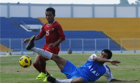 Pemain Tim Nasional Indonesia U-22, Bayau (kiri), berebut bola dengan pemain Tim Sepakbaola PON Riau, Cecep Arifin (kanan), saat pertandingan laga uji coba di Stadion Kaharudin Nasution Rumbai, Pekanbaru, Riau, (30/6). 