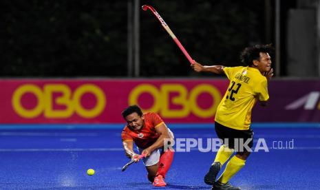 Pemain timnas hoki putra Indonesia di SEA Games 2023 Kamboja, Asrul Alam (kiri), memukul bola.