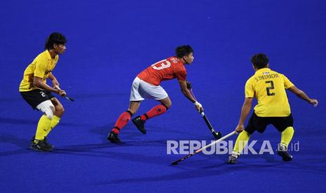 Pemain timnas hoki indoor putra Indonesia Revo Priliandro (tengah) menggiring bola lawan-lawannya.