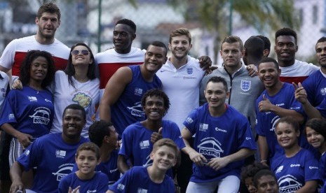 Pemain Timnas Inggris berposes bersama warga Brasil saat mereka mengunjungi kompleks olahraga di Ricinha di Rio de Janeiro pada Senin (9/6). 