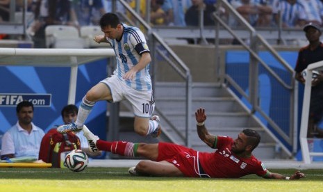 Pemain Timnas Iran, Ashkan Dejagah (kanan), berebut bola dengan striker Argentina, Lionel Messi, di laga Grup F Piala Dunia 2014 Brasil di Stadion Mineirao, Belo Horizonte, Sabtu (21/6). 