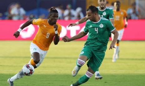 Pemain timnas Pantai Gading, Wilfried Zaha (kiri), berebut bola dengan pemain Timnas Aljazair, Djamel Benlamri, dalam laga perempat final Piala Afrika 2019 di Stadion Suez, Mesir, Kamis (11/7).