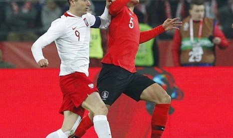  Pemain timnas Polandia Robert Lewandowski (kiri), berebut bola dengan pemain Korea Selatan Hyun-soo Jang, dalam laga persahabatan internasonal yang berlangsung di Chorzow, Polandia, Selasa (27/3) malam waktu setempat. 