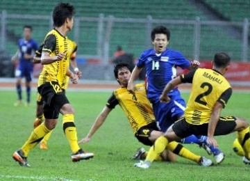 Pemain Timnas Thailand, Natarid Thammroddodpon (biru), dikerubuti pemain Timnas Malaysia saat pertandingan lanjutan kualifikasi Grup A SEA Games ke-26 di Stadion Utama Gelora Bung Karno, Jakarta, Rabu (9/11). 