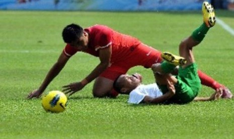 Pemain Timnas U23 Indonesia, Ferdinand Sinaga (kanan), terjatuh setelah dilanggar pemain Singapura di laga Grup A cabang sepak bola SEA Games 2011.