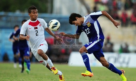   Pemain Timor Leste Nidio Octavio Das Dores Neto (putih) berebut bola dengan pemain Laos Sisawad Dalavong di Stadion Delta Sidoarjo, Jawa Timur, Ahad (22/9). (Republika/Edwin Dwi Putranto)