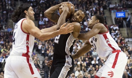 Pemain Toronto Raptors, Demar Derozan (kanan), berupaya menghalangi pemain San Antonio Spurs, Kawhi Leonard (tengah), dalam pertandingan NBA di Toronto pada Rabu (9/12).  