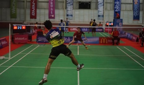 Pemain Universitas Surabaya (UBAYA) M Mirza (baju biru) melakukan smash ke daerah pertahanan pemain UPH Vicky Vendi dalam LIMA Badminton Putra