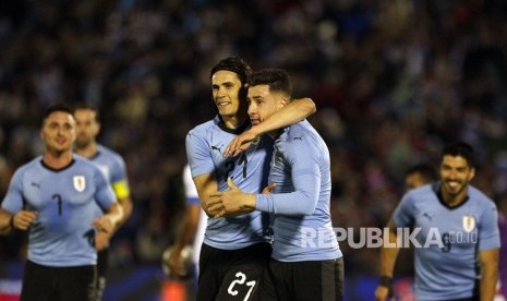 Pemain Uruguay, Jose Gimenez, merayakan gol dengan rekan setim Edinson Cavani pada laga persahabatan lawan Uzbekistan di Montevideo, Uruguay, Kamis (7/6).