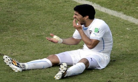 Pemain Uruguay Luis Suarez memegang giginya setelah menjalankan ke bahu Italia Giorgio Chiellini selama grup D Piala Dunia pertandingan sepak bola antara Italia dan Uruguay di Arena das Dunas di Natal, Brasil, Selasa, Selasa (24/6). (Pemain Uruguay Luis Su