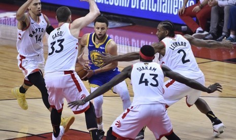 Pemain Warriors Stephen Curry mencoba melewati pemain Raptors.