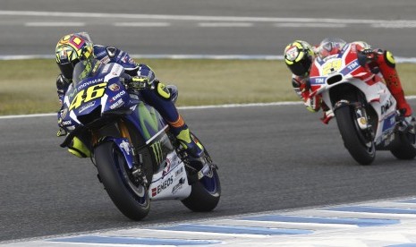 Pembalap asal Italia Valentino Rossi (kiri) dari Movistar Yamaha dan Andrea Iannone (kanan) sedang pemanasan di Jerez Circuit sebelum dimulainya balapan MotoGP di Jerez, Ahad (24/4).