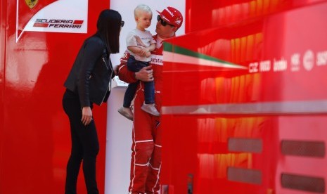 Pembalap Ferrari, Kimi Raikkonen bersama istri, Minttu Virtanen sambil menggendong anaknya, Robin pada sesi tes pramusim di sirkuit Catalunya, Barcelona, Spanyol, Jumat (10/3). Raikkonen menjadi yang tercepat pada tes pramusim tahun ini.