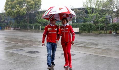 Pembalap Ferrari, Kimi Raikkonen (kiri) berjalan di paddock sirkuit Shanghai, Cina, Kamis (6/4). Cuaca buruk mengakibatkan dibatalkannya sesi latihan bebas GP Cina pada hari ini.