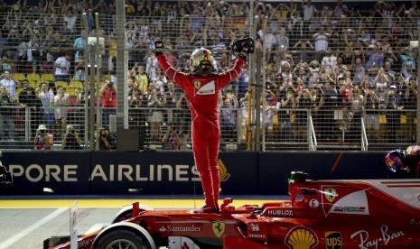 Pembalap Ferrari, Sebastian Vettel memberikan salam kepada penonton GP Singapura setelah berhasil meraih posisi start terdepan pada babak kualifikasi, Sabtu (16/9).