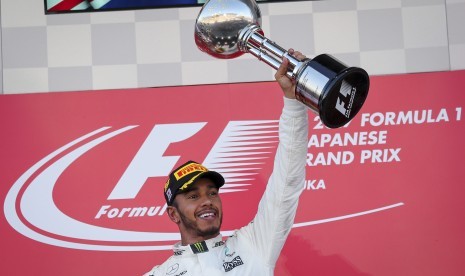 Pembalap Mercedes, Lewis Hamilton mengangkat trofi juara GP Jepang setelah menjadi yang tercepat pada balapan di Sirkuit Suzuka, Ahad (8/10).