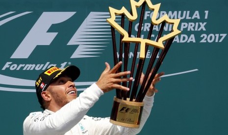 Pembalap Mercedes, Lewis Hamilton mengangkat trofi juara GP Kanada di Sirkuit Gilles Villeneuve, Ahad (11/6).